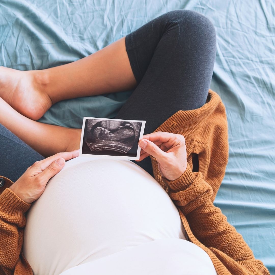 A pregnant mother to be holding an ultrasound image of her baby